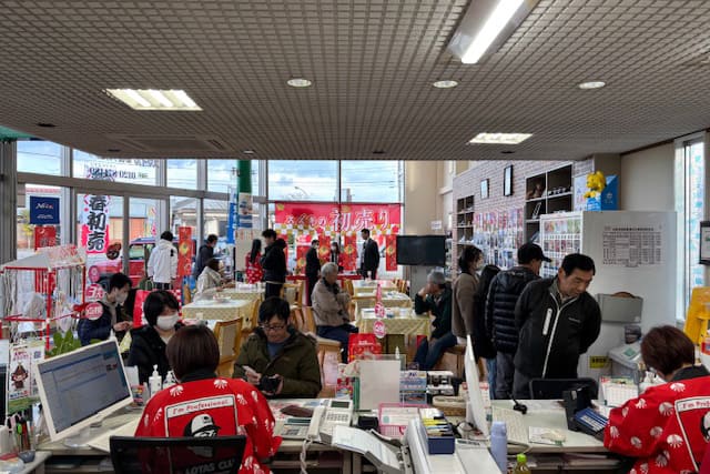 赤いユニフォームをきたスタッフが窓口業務をしている様子