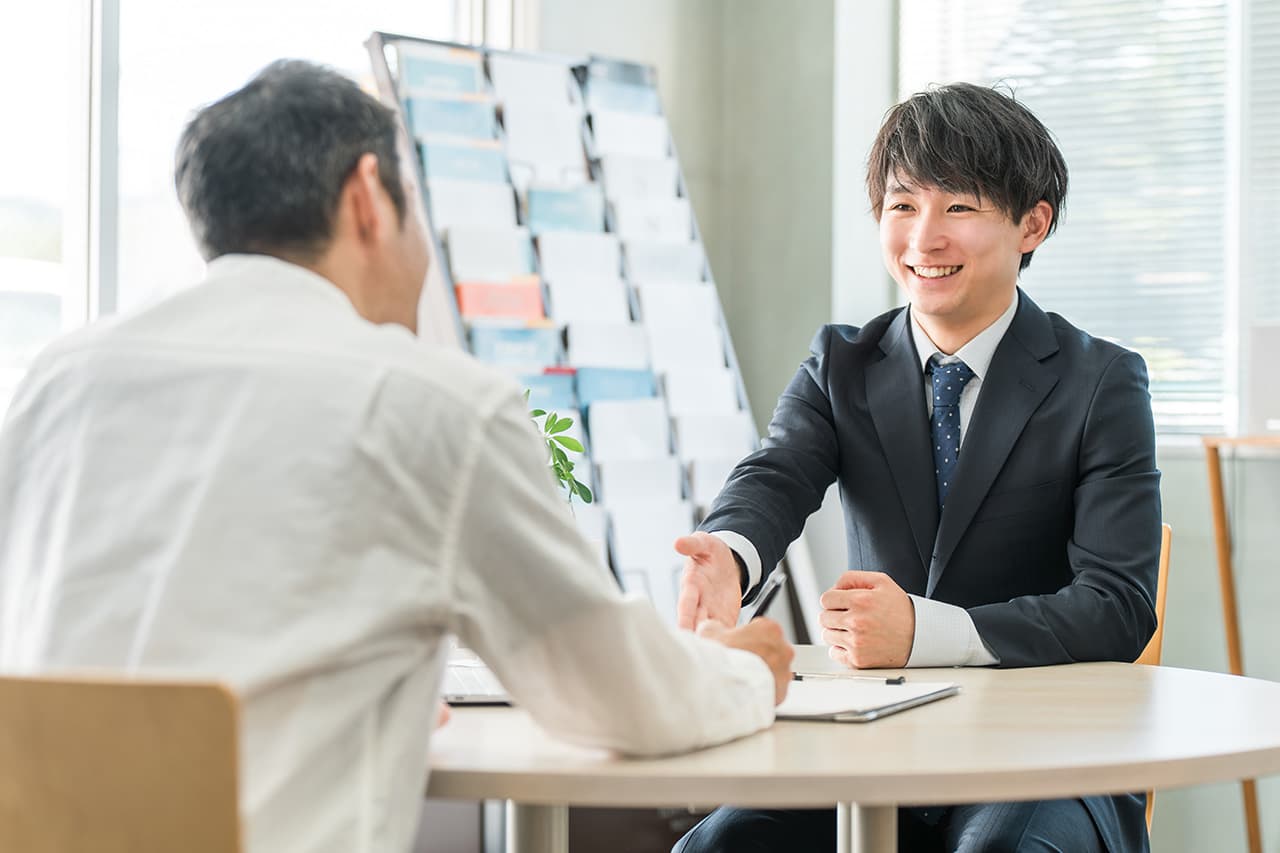 男性が男性客に笑顔で接客している様子